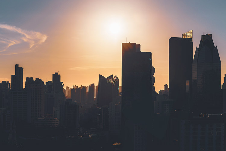 Panama City skyline in silhouette at sunrise with blue sky, glowing sun, and warm golden light reflecting off skyscrapers – panoramic urban cityscape view captured in the early morning.